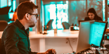 Homem de óculos e camisa social utilizando notebook